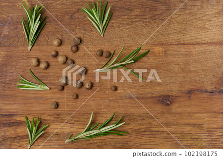 Dry allspice peas and rosemary branches on a wooden background Dry allspice peas and rosemary branches on a wooden background 102198175
