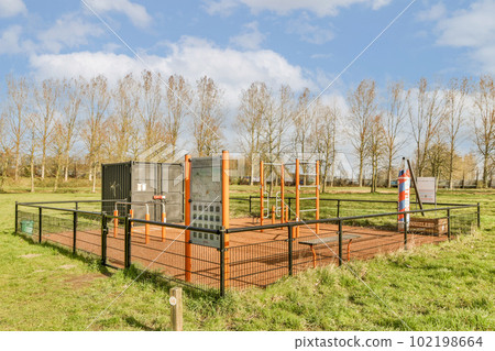 an outdoor play area in the middle of a park with trees and green grass on both sides, there is a slide set up 102198664