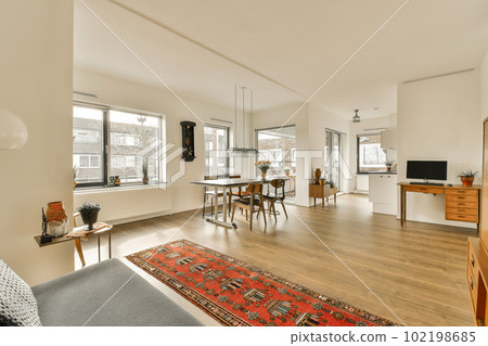 a living room with hardwood flooring and white walls in the center of the room, there is a red rug on the floor a living room with hardwood flooring and white walls in the center of the room, there is a red rug on the floor 102198685