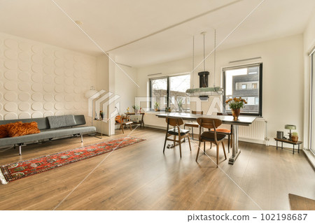 a living room with wood flooring and white walls, including a grey couch in the area has a red rug on the floor a living room with wood flooring and white walls, including a grey couch in the area has a red rug on the floor 102198687