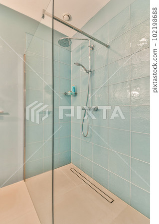 a bathroom with blue tiles on the wall and shower head mounted to the wall in front of the glass door a bathroom with blue tiles on the wall and shower head mounted to the wall in front of the glass door 102198688
