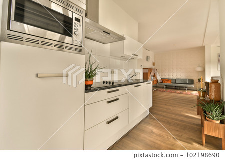 a kitchen with wood flooring and white appliances on the wall, along with an open door leading to the living room 102198690