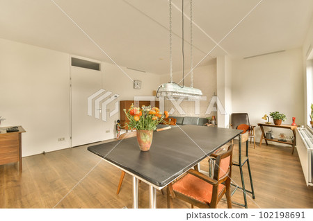 a kitchen and dining area in a house with wood flooring, white walls, wooden furniture and an orange chair a kitchen and dining area in a house with wood flooring, white walls, wooden furniture and an orange chair 102198691