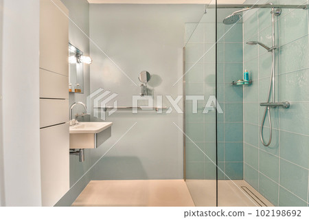 a modern bathroom with blue tiles and glass shower door, sink and toilet in the background is white tile on the floor a modern bathroom with blue tiles and glass shower door, sink and toilet in the background is white tile on the floor 102198692