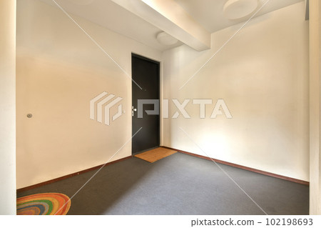 an empty room with a door and rug on the floor in front of the doorway to the left is a black door an empty room with a door and rug on the floor in front of the doorway to the left is a black door 102198693