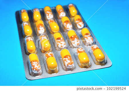 capsules in a blister, a medicine, tablets, vitamins in the form of granules in a yellow capsule, blur as a creative technique of the author, close-up capsules in a blister, a medicine, tablets, vitamins in the form of granules in a yellow capsule, blur as a creative technique of the author, close-up 102199524