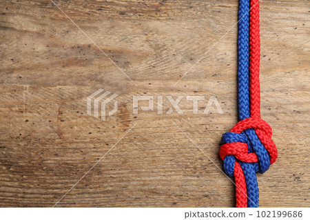 Top view of colorful ropes tied together on wooden background, space for text. Unity concept 102199686