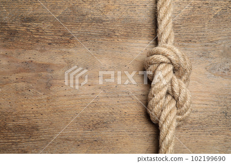 Top view of linen rope with knot on wooden background, space for text. Unity concept 102199690