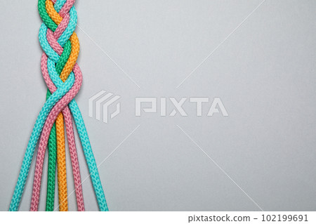 Top view of braided colorful ropes on light grey background, space for text. Unity concept 102199691