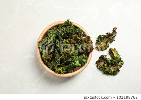 Tasty baked kale chips on grey marble table, flat lay Tasty baked kale chips on grey marble table, flat lay 102199762