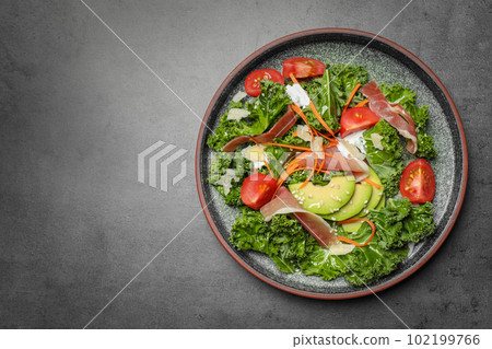 Delicious kale salad with prosciutto served on grey table, top view. Space for text 102199766