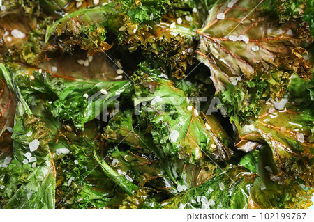 Tasty baked kale chips as background, closeup 102199767