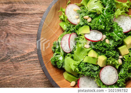 Delicious kale salad on wooden table, top view 102199782