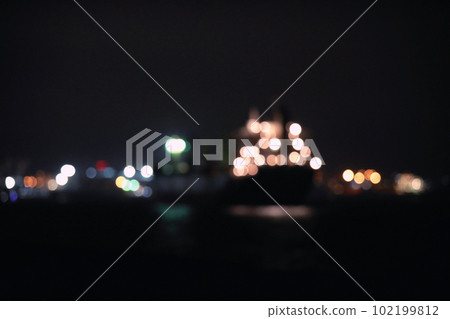 Blurred view of bulk carrier in roads at night. Bokeh effect Blurred view of bulk carrier in roads at night. Bokeh effect 102199812