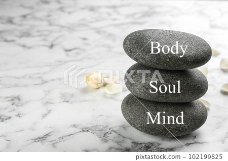 Stones with words MIND, BODY, SOUL on marble background, space for text. Zen lifestyle 102199825