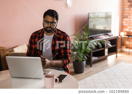 Happy indian man freelancer or entrepreneur have video conference talking, working remotely online at home office - video call and diversity concept Happy indian man freelancer or entrepreneur have video conference talking, working remotely online at home office - video call and diversity concept 102199880