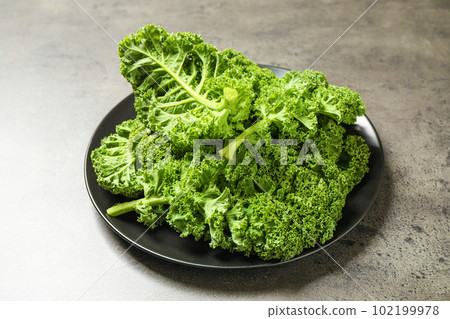 Fresh green kale leaves on grey table Fresh green kale leaves on grey table 102199978