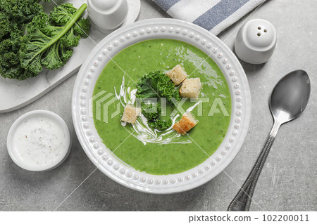 Tasty kale soup with croutons served on grey table, flat lay 102200011