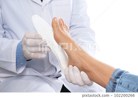 Male orthopedist fitting insole on patient's foot against white background, closeup 102200266