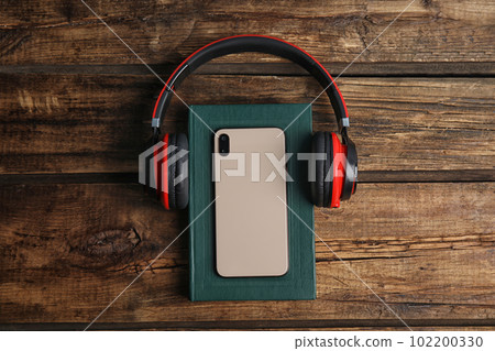Book, modern headphones and smartphone on wooden table, flat lay 102200330