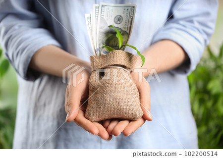 Woman holding sack with dollars and green sprout, closeup. Money savings Woman holding sack with dollars and green sprout, closeup. Money savings 102200514