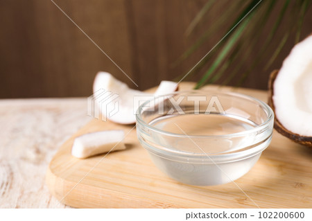 Coconut oil in glass bowl on wooden board, closeup Coconut oil in glass bowl on wooden board, closeup 102200600