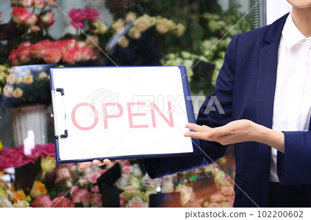 Female business owner holding OPEN sign near flower shop, closeup Female business owner holding OPEN sign near flower shop, closeup 102200602