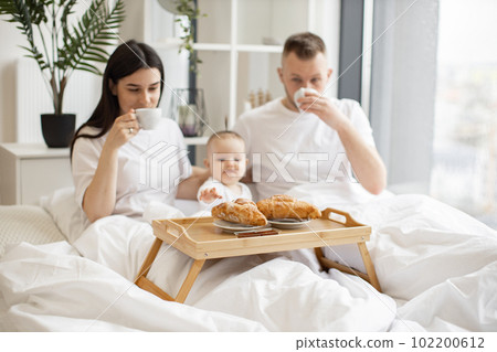 Small family of three having meal together in home interior Small family of three having meal together in home interior 102200612