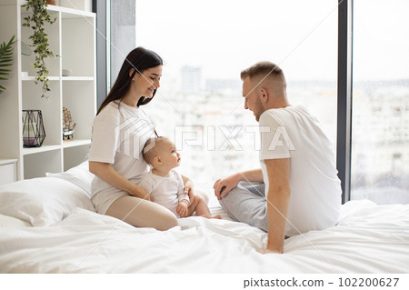 Mom and dad taking care of daughter during weekend indoors 102200627
