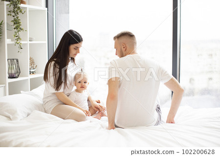 Mom and dad taking care of daughter during weekend indoors 102200628