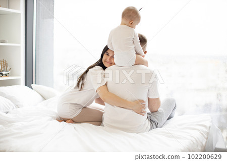Wife embracing husband with kid on shoulders in apartment 102200629