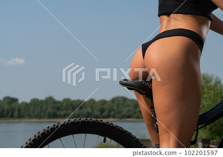 Caucasian woman in short shorts rides a bike on a hot summer day. 102201597