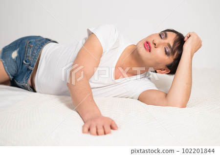 Caucasian transgender man lies on bed. Gay posing in the bedroom. Caucasian transgender man lies on bed. Gay posing in the bedroom. 102201844