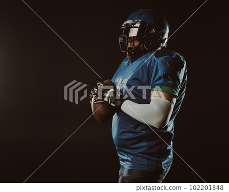 An Asian man with a red beard in a blue American football uniform throws a ball against a black background. An Asian man with a red beard in a blue American football uniform throws a ball against a black background. 102201848