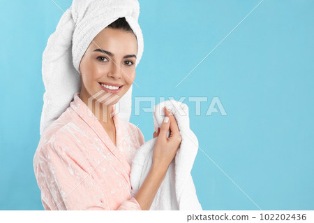 Young woman wiping hands with towel on light blue background Young woman wiping hands with towel on light blue background 102202436