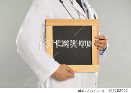 Doctor holding blackboard with word HEMORRHOID on light grey background, closeup Doctor holding blackboard with word HEMORRHOID on light grey background, closeup 102202452