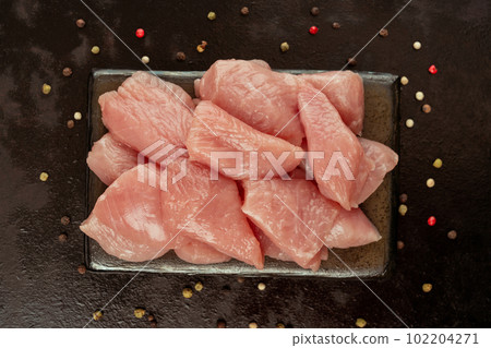 Raw pieces of turkey meat on a ceramic board on a black background.Close-up.Ogranic food and healthy eating.Chicken fillet.Fresh pieces of turkey meat.Raw chicken. Raw pieces of turkey meat on a ceramic board on a black background.Close-up.Ogranic food and healthy eating.Chicken fillet.Fresh pieces of turkey meat.Raw chicken. 102204271