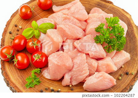 Fresh pieces of turkey meat.Raw chicken.Close up.Raw pieces of turkey meat with greens and tomatoes on a wooden board against a white background.Ogranic food and healthy eating.chicken fillet. Fresh pieces of turkey meat.Raw chicken.Close up.Raw pieces of turkey meat with greens and tomatoes on a wooden board against a white background.Ogranic food and healthy eating.chicken fillet. 102204287