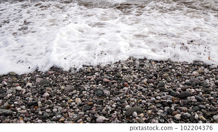 Views along  a pebbled beach as waves reach the strand line 102204376