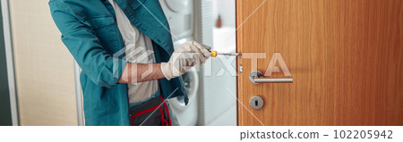 Locksmith workman in uniform installing door knob. Professional repair service Locksmith workman in uniform installing door knob. Professional repair service 102205942