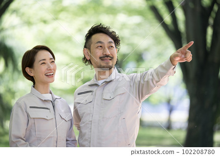 一名工人用手指指著新鮮綠色植物中的植物和木材 一名工人用手指指著新鮮綠色植物中的植物和木材 102208780