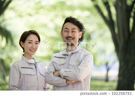 一位身穿工作服的工人雙臂交叉，在新鮮的綠色植物中抬頭仰望，複製空間看著相機 102208781