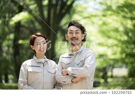 一位身穿工作服的工人雙臂交叉，在有復制空間的新鮮綠色植物中抬頭的形象 102208782