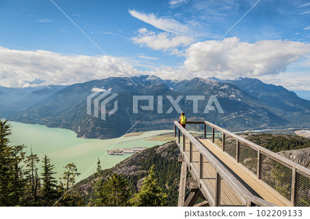 Squamish, British Columbia nature with hiking woman hiker in looking at view of amazing landscape on viewing platform on famous Sea to Summit hike in BC. Popular outdoor activity destination in Canada Squamish, British Columbia nature with hiking woman hiker in looking at view of amazing landscape on viewing platform on famous Sea to Summit hike in BC. Popular outdoor activity destination in Canada 102209133