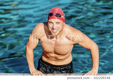 Portrait of swimmer. Sport swimmer athlete man at swimming pool. Active lifestyle healthy fit man wearing cap and swim goggles Portrait of swimmer. Sport swimmer athlete man at swimming pool. Active lifestyle healthy fit man wearing cap and swim goggles 102209146
