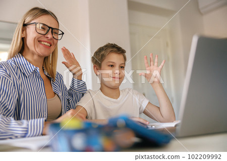 Smiling mom and son talking by video call with friends of family and waving Hi Smiling mom and son talking by video call with friends of family and waving Hi 102209992