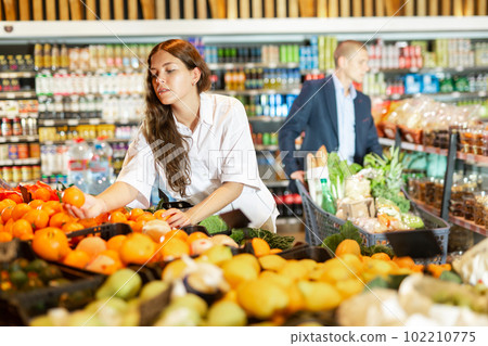 Focused young girl selects ripe tangerines in a supermarket 102210775