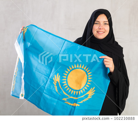 Happy young woman dressed in traditional islamic clothes with kazakh flag Happy young woman dressed in traditional islamic clothes with kazakh flag 102210888