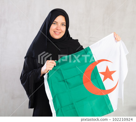 Happy young woman dressed in traditional islamic clothes with algerian flag Happy young woman dressed in traditional islamic clothes with algerian flag 102210924