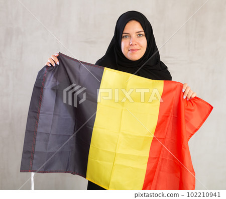 Balanced Muslim woman in traditional black hijab holds flag of Belgium 102210941